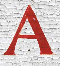 A photograph of a capital letter A painted on a wall. The paint behind it is cracking.