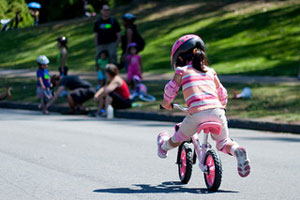 A photograph of a little girl riding away on a bike