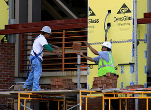A photograph of two men laying bricks in a large structure