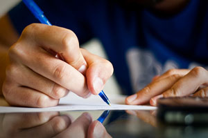 A close-up image of a student holding a pen and paper.