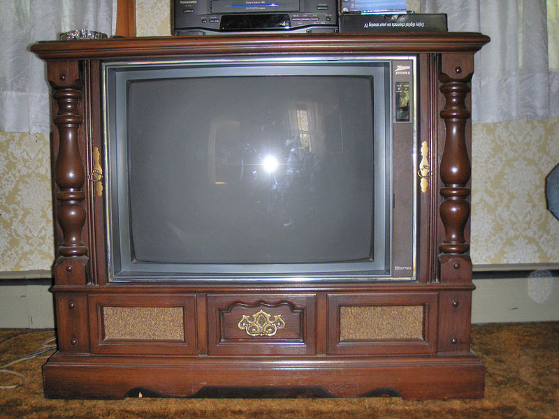 An old television set from the 1970s, built into a heavy wooden cabinet easily three feet wide, two feet high, and a foot and a half deep.