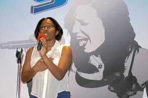 A photograph of a woman singing into a microphone at an audition.