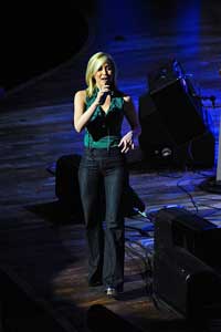 A photograph of a woman singing on stage.