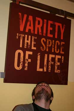 A photograph of a man looking up at a sign that reads “Variety is the Spice of Life.”