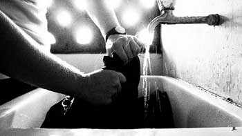 = A photograph of a man washing clothes in a sink