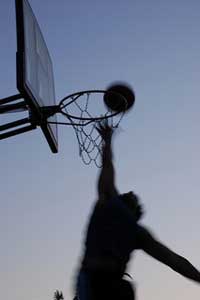 A photograph of a young man dunking a basketball in an outdoor net