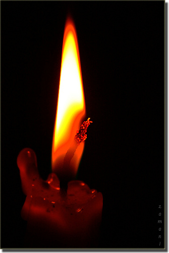 a close-up picture of a candle, burning with a bright flame but slowly running out of fuel