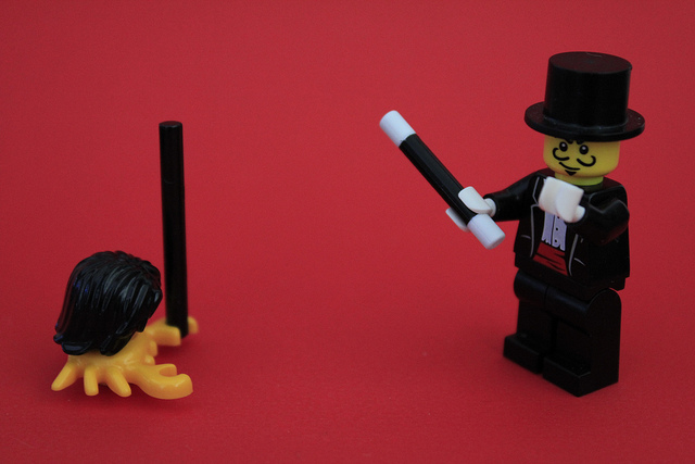 A pair of Lego figurines; one is a magician holding a wand and wearing a top hat. The other is a crab with Lego hair holding a wand.