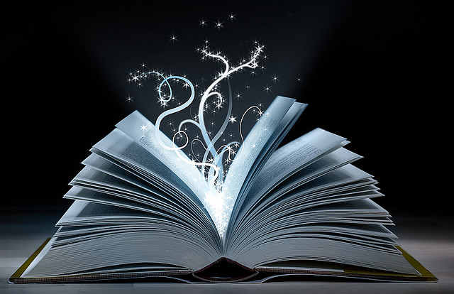A book, lying on its spine, pages leaved open and vines of light emitting from within