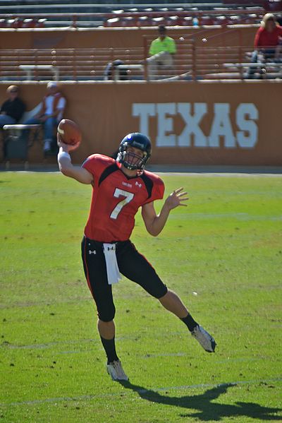 A photograph of a highschool aged quarterback throwing a football.