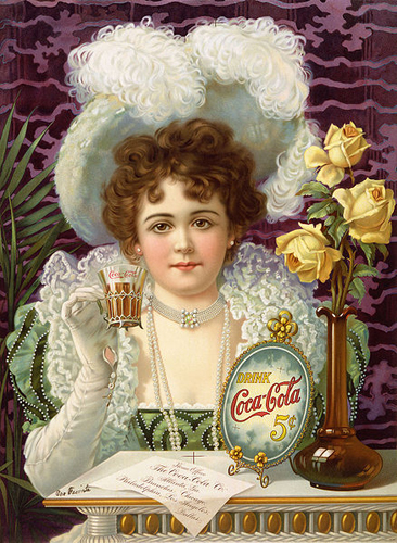 An 1890s advertising poster shows a woman in fancy clothes (vaguely influenced by 16th- and 17th-century styles) drinking Coke. The card on the table says "Home Office, The Coca-Cola Co. Atlanta, Ga. Branches: Chicago, Philadelphia, Los Angeles, Dallas". There are cross-shaped color registration marks near the bottom-center and top-center (which presumably would have been removed for a production print run). Someone has crudely written on it at lower left (with a fountain pen that was apparently leaking), "Our Favorite" [sic]. 