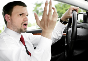 A man driving with his hands off the steering wheel.