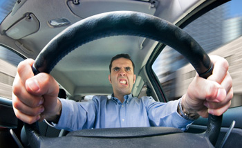 A man driving while gripping the wheel with extreme road rage.