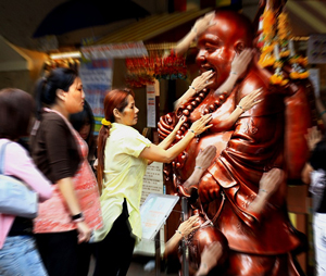 A photograph of women touching a statue of a Buddha