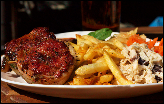 A photograph of a main course of a dinner. It is a steak, French Fries, and a salad