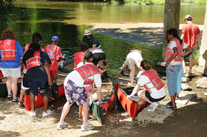 A photograph of a group of campers getting ready to go canoeing.