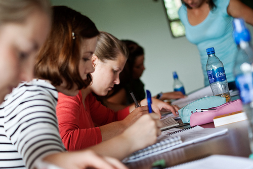 A photograph of several female students writing in notebooks.