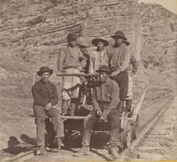 Image of Chinese workers sitting on a railcar on a section of a railroad