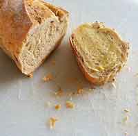 A photo of bread broken into two parts, crumbs between them.
