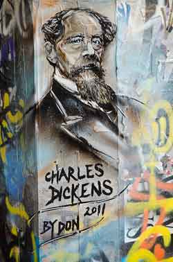 A mural of Charles dickens painted on graffitied wall of a building.