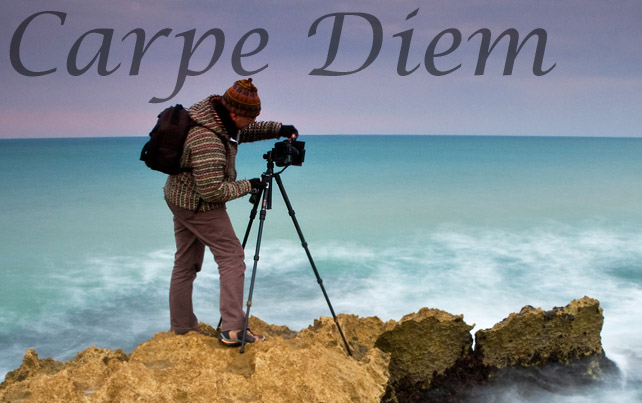 A photographer standing on dangerous rocks gets ready to take a photo of the sea.