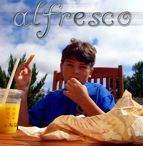 A boy eats French fries outside, against a cloudy sky.