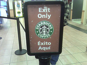 A Starbuck’s sign that reads: Exit Only and in Spanish it incorrectly states: <i />Éxito Aquí</i>.