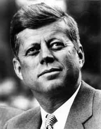 A photograph portrait of President John F. Kennedy. He is a man in his 40s wearing a jacket and tie.