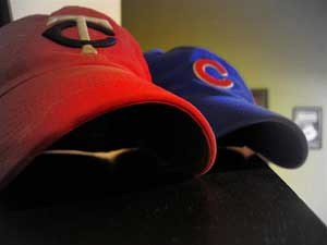 A photograph of two baseball caps on a table or shelf