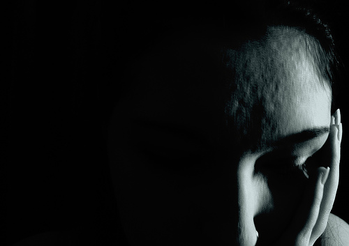 A photograph of a woman by herself in a darkened room