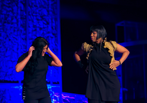 A photograph of two actresses acting out a scene on stage