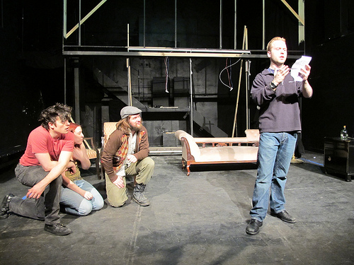 A photograph of a play rehearsal; One of the characters is delivering a monologue.