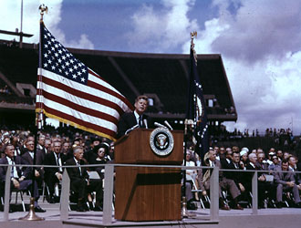 A photograph of President John F. Kennedy giving a speech at Rice Stadium in Houston, TX in 1962.