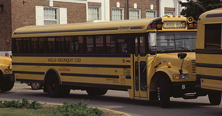 A school bus in close company with two other busses, in front and behind