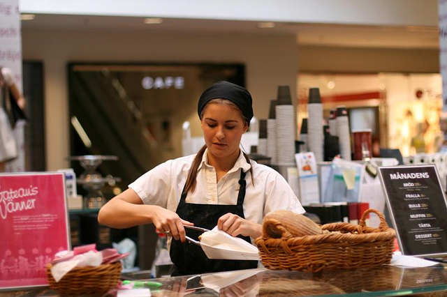 A photograph of a young woman working in a bakery