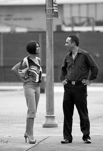 A photograph of a man and a woman having a discussion on a street corner