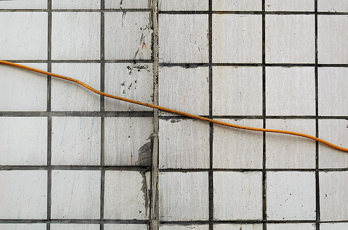 A photo of a cord running along a tiled wall in such a way that it looks like a line on a graph
