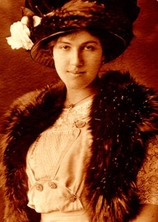 A photograph of a an aristocratic woman form the 1920s. She is wearing a fancy hat and a mink stole.