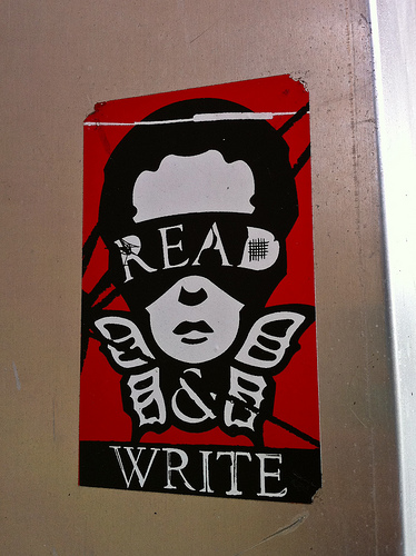 A photograph of a poster that reads: Read & Write. The words are part of an image of a person’s head with butterfly wings under it