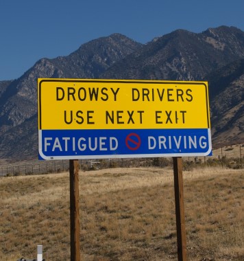 A photograph of a highway sign informing drowsy drivers to use the next exit