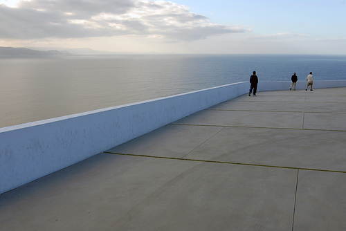 A photograph of an isolated viewing place near the ocean, There are three people in the frame