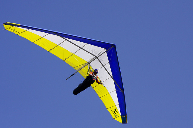 A photograph of a person hang gliding with a clear sky in the background