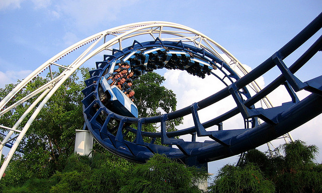 A photograph of people in the middle of a cork screw turn in a roller coaster