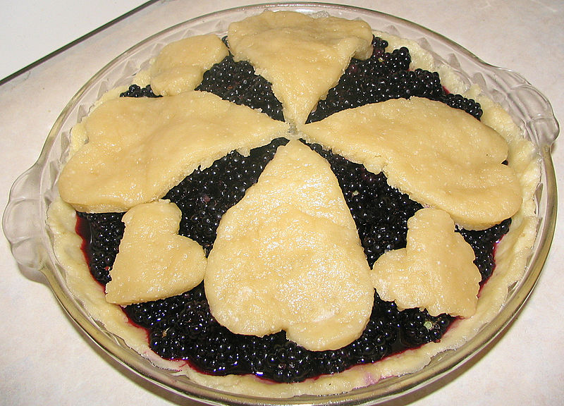 A photograph of a fancy blackberry pie with a crust resembling hearts