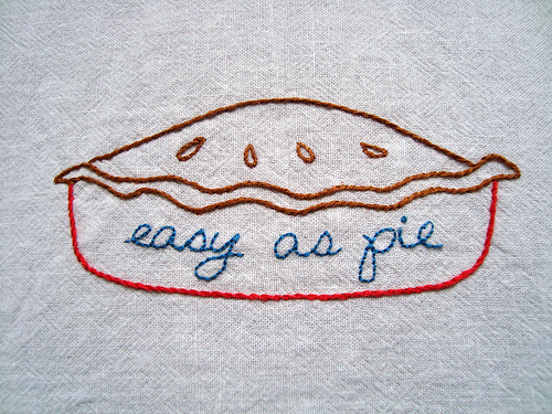 A photograph of an image of a pie sewn into linen. It has the phrase, “easy as pie” written in it