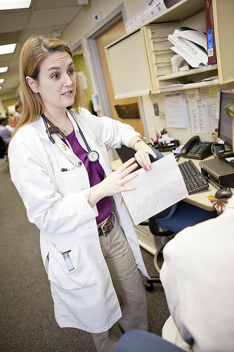 A photograph of a doctor consulting with another doctor. She is holding a chart in one hand