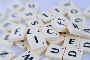photo of a pile of scrabble letters, each one printed in black on a plastic, white square