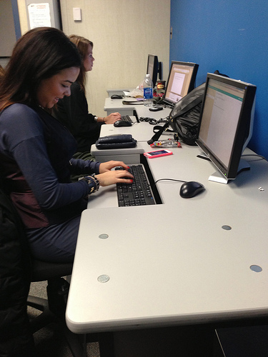 A photograph of two female students typing on computers in a computer lab.