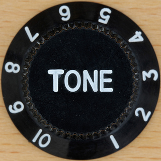 A photograph of an electric guitar’s tone knob