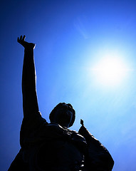 A photograph of a statue of a man reaching towards the sky